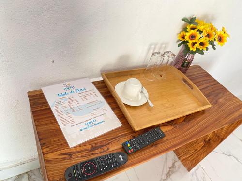 a wooden table with a book and two remote controls at Samuge Village in Namacurra