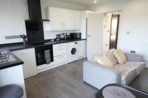 a kitchen with white cabinets and a couch in a room at Hatton apartments HEATHROW AIRPORT- FREE parking-Free underground to and from Heathrow Airport Hatton Cross SEE picture-SEE LONDON fast Hatton cross to central London 30min in London