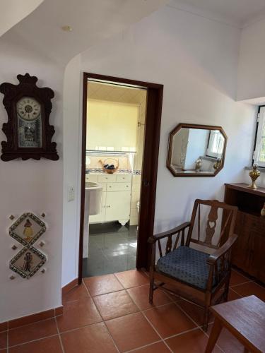 a room with a chair and a mirror and a clock at Moinho da Saudade in Alcabideche