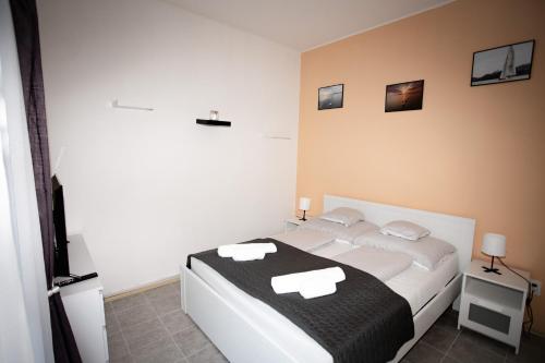 a bedroom with a white bed with a black blanket at Harmónia apartman in Zánka