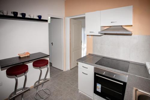 a kitchen with white cabinets and red stools at Harmónia apartman in Zánka
