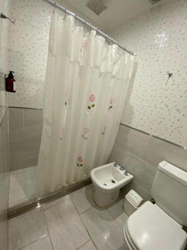 a bathroom with a toilet and a shower curtain at Clomplejo MUNAY con piscina y parking in Villa Cura Brochero