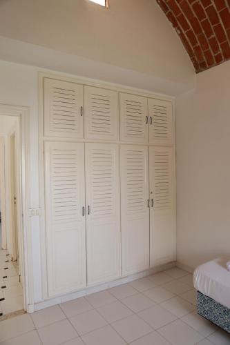 a white bedroom with white cabinets and a brick wall at Les villas Africa Jade in Korba