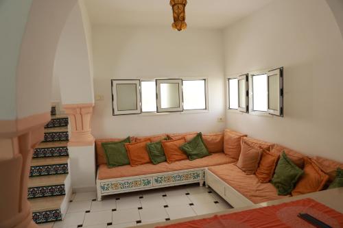a living room with an orange couch with green pillows at Les villas Africa Jade in Korba
