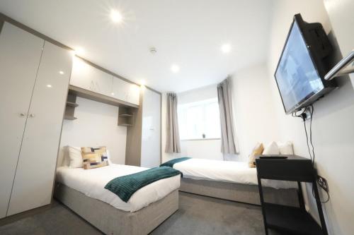 a bedroom with two beds and a flat screen tv at Hatton apartments HEATHROW AIRPORT- FREE parking-Free underground to and from Heathrow Airport Hatton Cross SEE picture-SEE LONDON fast Hatton cross to central London 30min in London
