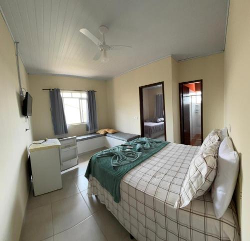 a bedroom with a bed and a living room at Pousada Fênix,com piscina -250 METROS DA PRAIA in Pontal do Paraná