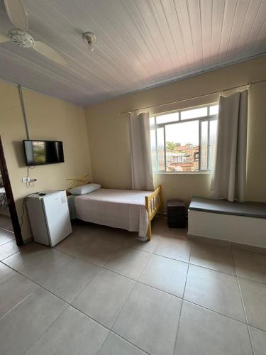 a bedroom with a bed and a window and a tv at Pousada Fênix,com piscina -250 METROS DA PRAIA in Pontal do Paraná