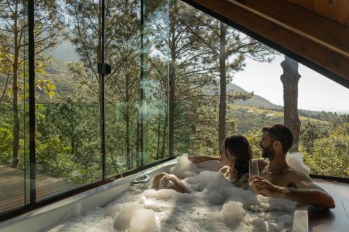 a man and woman sitting in a bath tub with bubbles at Chalés do Tabuleiro in Palhoça