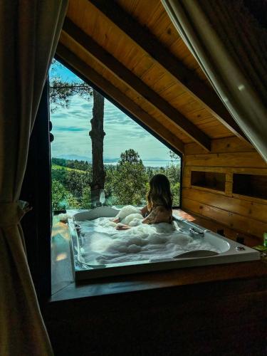 a woman in a bath tub in a room with a window at Chalés do Tabuleiro in Palhoça