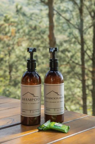 two bottles of syrup sitting on a wooden table at Chalés do Tabuleiro in Palhoça