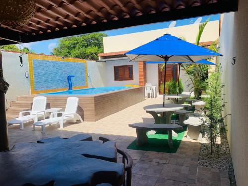 a patio with a table and an umbrella and a pool at Casa com piscina in Marechal Deodoro