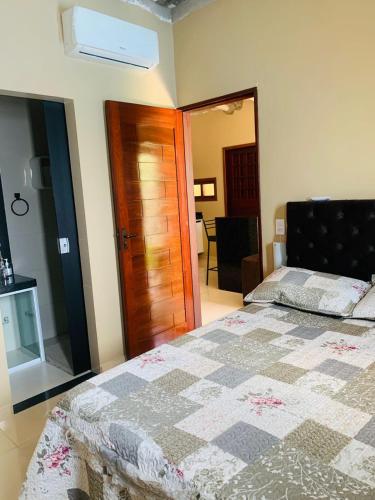 a bedroom with a bed with a quilt on it at Casa com piscina in Marechal Deodoro