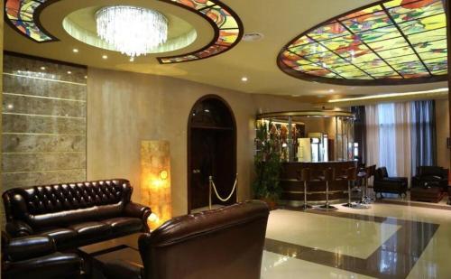 a lobby with leather chairs and stained glass windows at New Nairi Hotel Yerevan in Yerevan