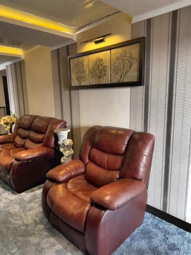 a living room with two chairs and a leather couch at New Nairi Hotel Yerevan in Yerevan