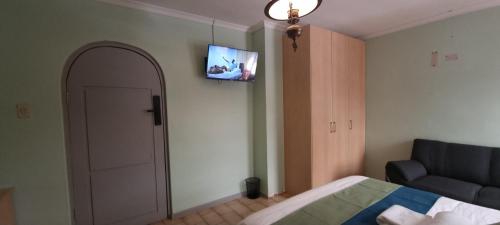 a bedroom with a couch and a television on the wall at Ojong's Guesthouse Ridgeworth - Bellville in Tyger Valley