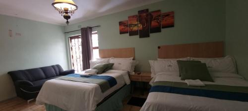 a room with two beds and a couch in it at Ojong's Guesthouse Ridgeworth - Bellville in Tyger Valley