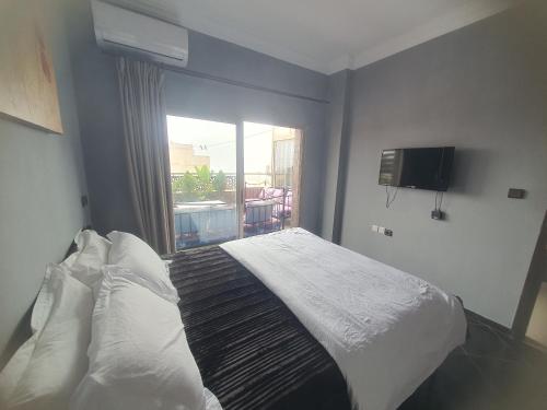 a bedroom with a bed and a window with a television at la sublime in Taghazout