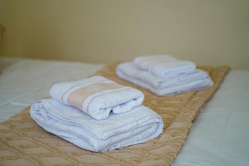 three towels are stacked on a tray on a bed at Les villas Africa Jade in Korba