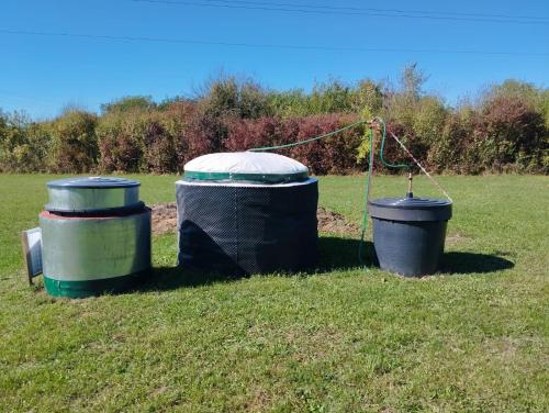 two trash cans sitting in the grass in a field at Blossom Cottage - Sustainable Tourism Retreat in Laktaši