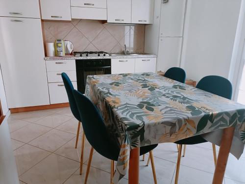 a kitchen with a table with blue chairs and a table cloth at Aeroporto & Fiera 30 in Seriate