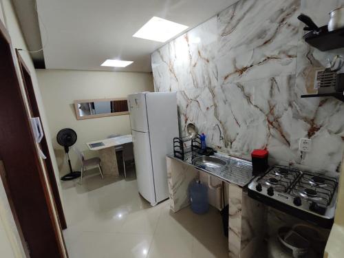 a kitchen with a stove and a white marble wall at Suíte Nazaré in Belém