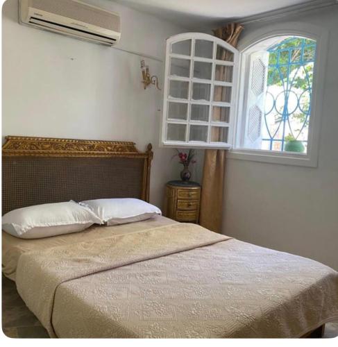 a bedroom with a bed with a window and a fan at La chambre dorée avec jardin privé in Dar Salah Bey