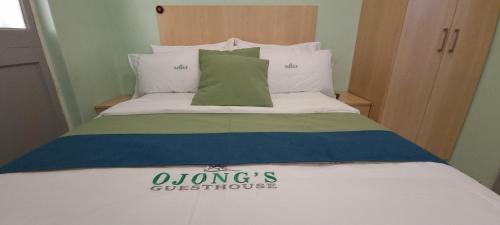 a bed with a green pillow on top of it at Ojong's Guesthouse Ridgeworth - Bellville in Tyger Valley