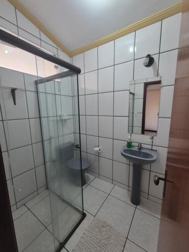 a bathroom with a glass shower and a sink at Flat MP PLUMA 201A in Araxá