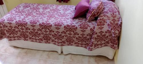 a bed with a pink blanket and pillows on it at Hostal el Arroyito in Ushuaia