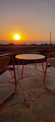 a table and a chair in front of a sunset at שיר ערש in Giv'at Yo'av