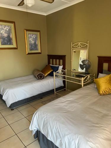 a bedroom with two beds and a mirror on the wall at ForgetMeNot Guesthouse Lydenburg in Lydenburg