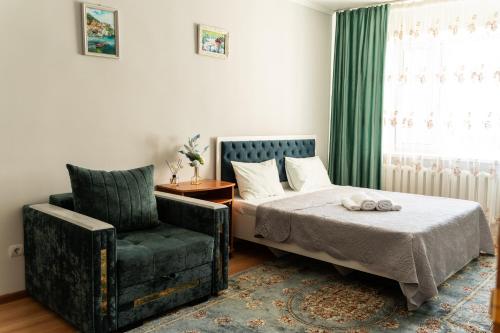 a bedroom with a bed and a chair at Уютная квартира в центре города in Taldykolʼ