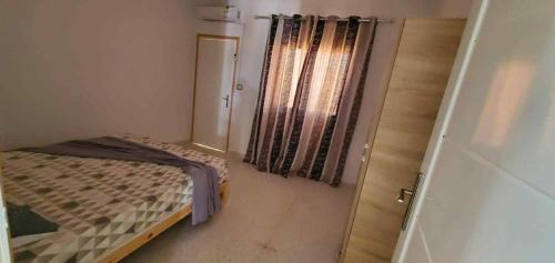 a small room with a bed and a window at Maison piscine privée in Bū Shammah
