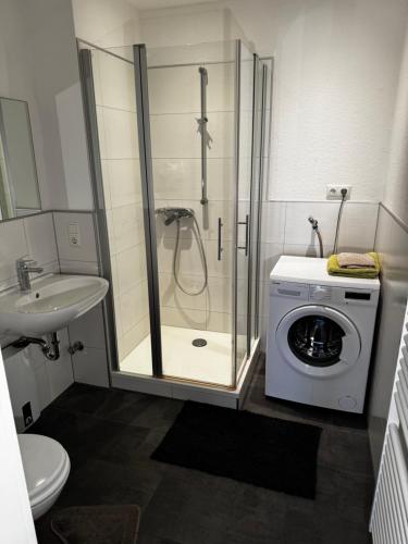 a bathroom with a shower and a washing machine at Kaiser-Rooms Stralsunder Ring 18 in Wolfsburg