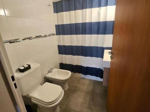 a bathroom with a toilet and a blue and white shower curtain at CHALET DE VACACIONES i in Ostende