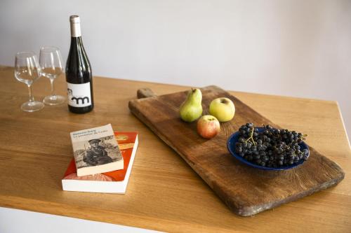a wooden table with a bottle of wine and a plate of fruit at Mas de Monge in Tarascon