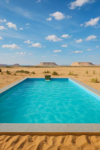 a blue swimming pool in the middle of the desert at sabrina camp in Siwa