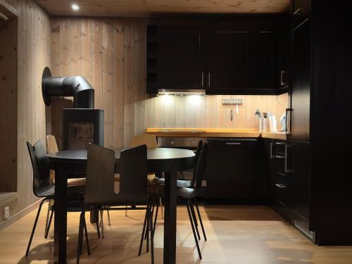 eine Küche mit schwarzen Schränken sowie einem Tisch und Stühlen in der Unterkunft Alpine Crown Trysil in Trysil