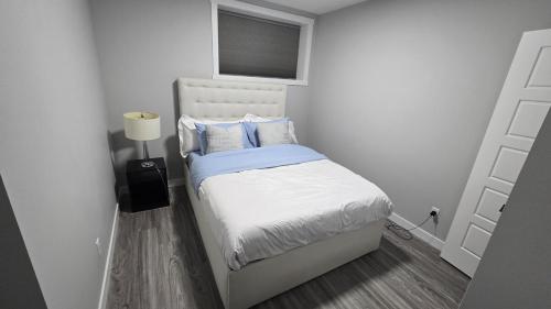 a small white bedroom with a bed with blue pillows at Royaldee Cozy Home 2beds & 2baths in Calgary