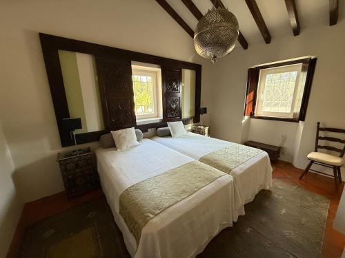 ein Schlafzimmer mit einem großen Bett und zwei Fenstern in der Unterkunft Casa da Retorta in Casa Branca