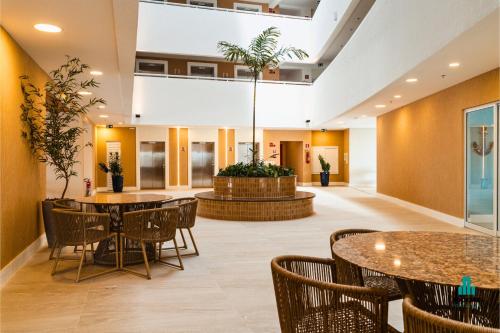 a lobby with tables and chairs and a potted tree at Aquarius Style by Holiday Stays in Fortaleza