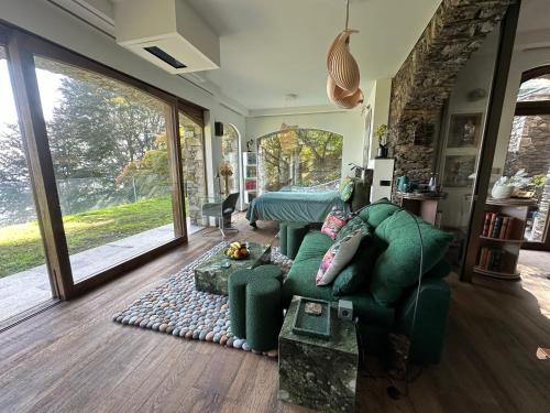 a living room with a green couch and a bed at Private Luxury Spa & Silence Retreat with Spectacular View over the Lake Maggiore in Stresa
