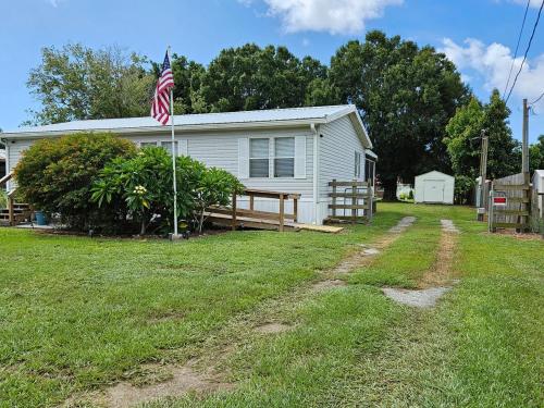 a white house with an american flag in the yard at Fisherman's Hideaway! Home on canal in Okeechobee! in Okeechobee