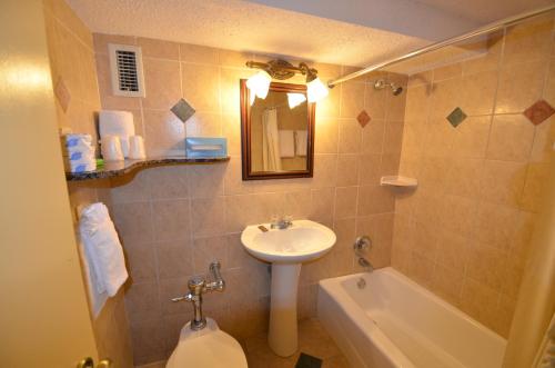 a bathroom with a sink and a toilet and a tub at Sea Club Ocean Resort in Fort Lauderdale
