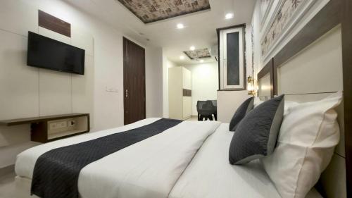 a bedroom with a large white bed with a flat screen tv at Hotel HomeAste 001 Near Yashobhoomi Convention Center in New Delhi