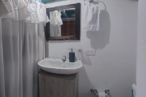 a bathroom with a white sink and a mirror at Hotel Veraneras del Quindío in Pueblo Tapao