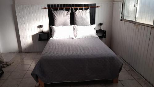 een slaapkamer met een groot bed met witte lakens en kussens bij Monoambiente in La Porteña