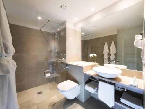 a bathroom with a sink and a toilet and a mirror at WONNEMAR Resort-Hotel in Wismar