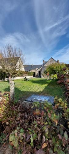 a yard with a house and a lawn with bushes at Petite maison de vacances in Cherrueix