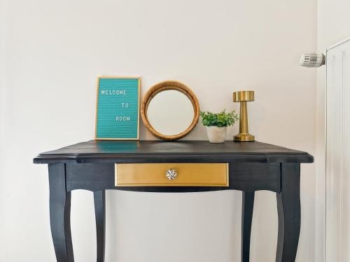 a black console table with a mirror and a lamp at Le Cocon - Terrasse & Parking - Calme in La Mézière
